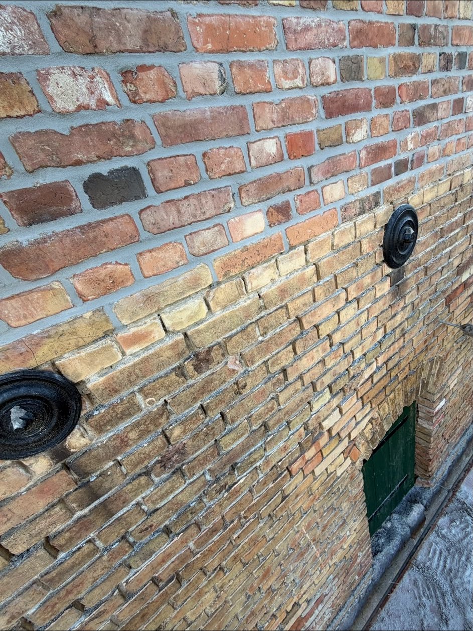 Detailaufnahme einer Klinkerwand: oben frisch verfugtes Mauerwerk mit hellem Mörtel, unten alte ausgewaschene und zurückliegende Fugen